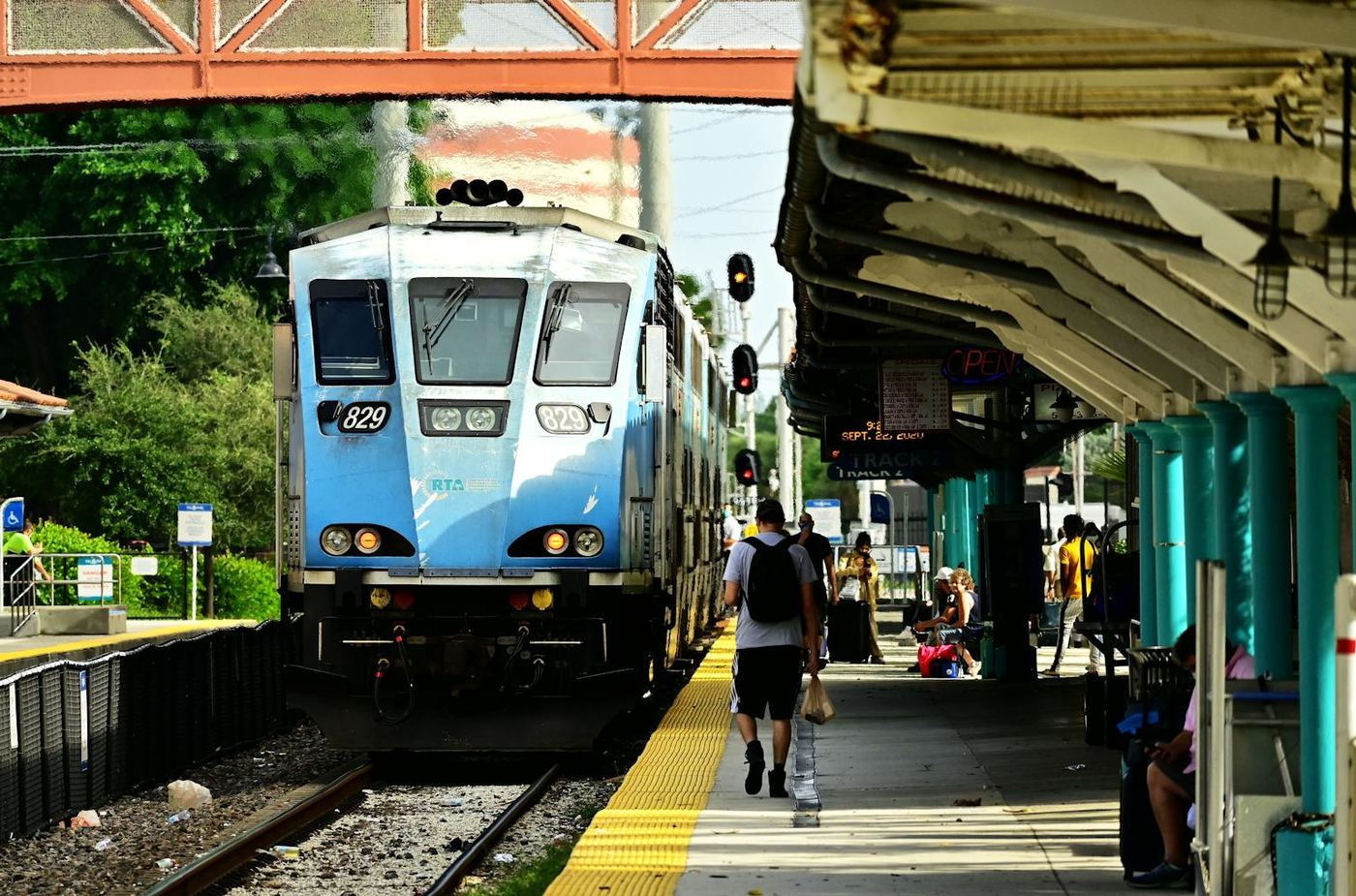 Blue train approaches a bustling station capturing daily commute life