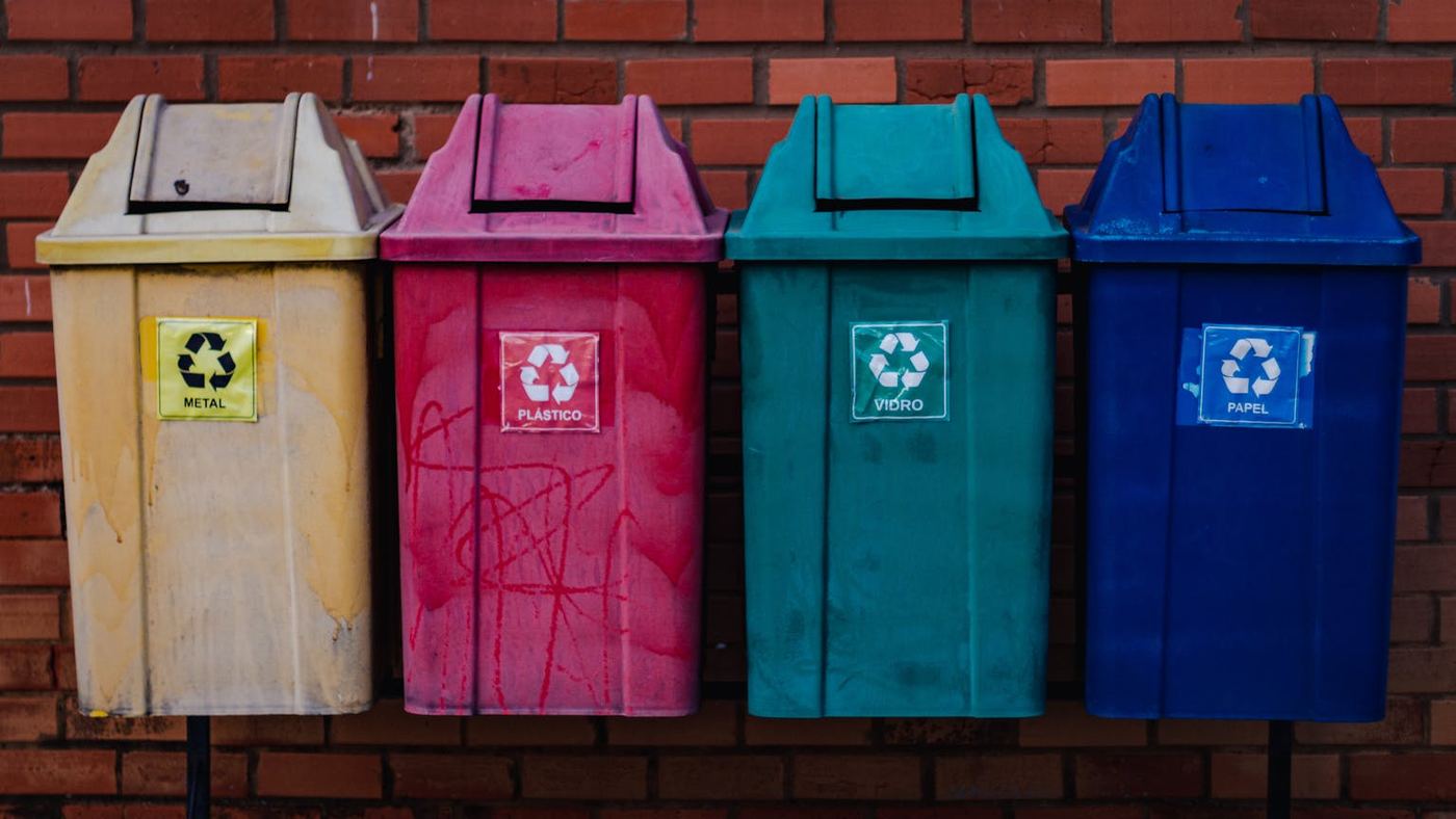 Four colorful recycling bins for metal plastic glass and paper against a brick wall in brazil