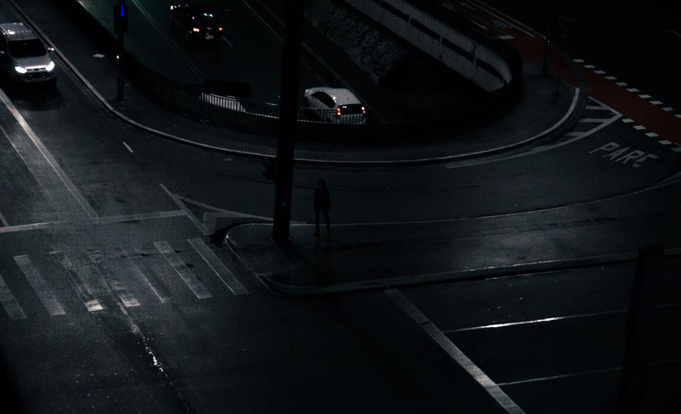 Nighttime urban intersection with cars and dim street lighting