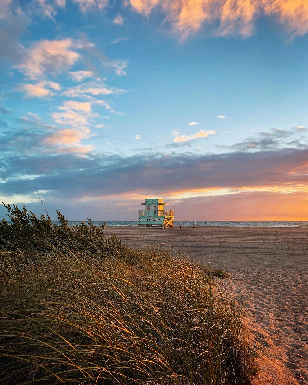 Stunning sunset over north miami beach with a lone lifeguard tower and serene coastline