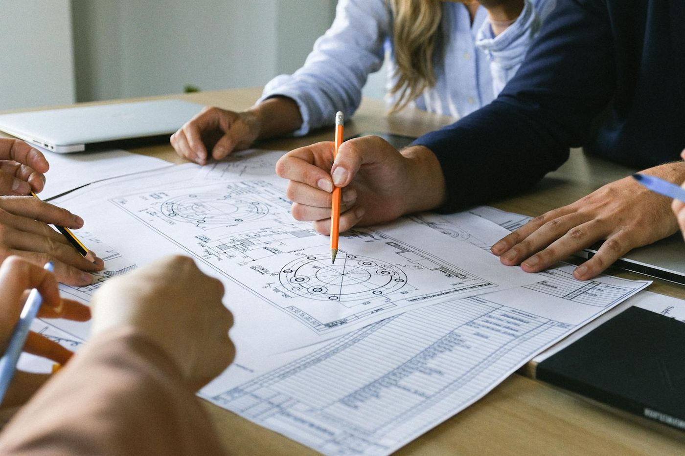 Team working on engineering plans discussing ideas at an office meeting