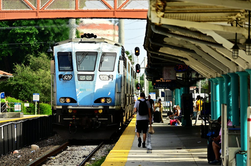 Blue train approaches a bustling station, capturing daily commute life.