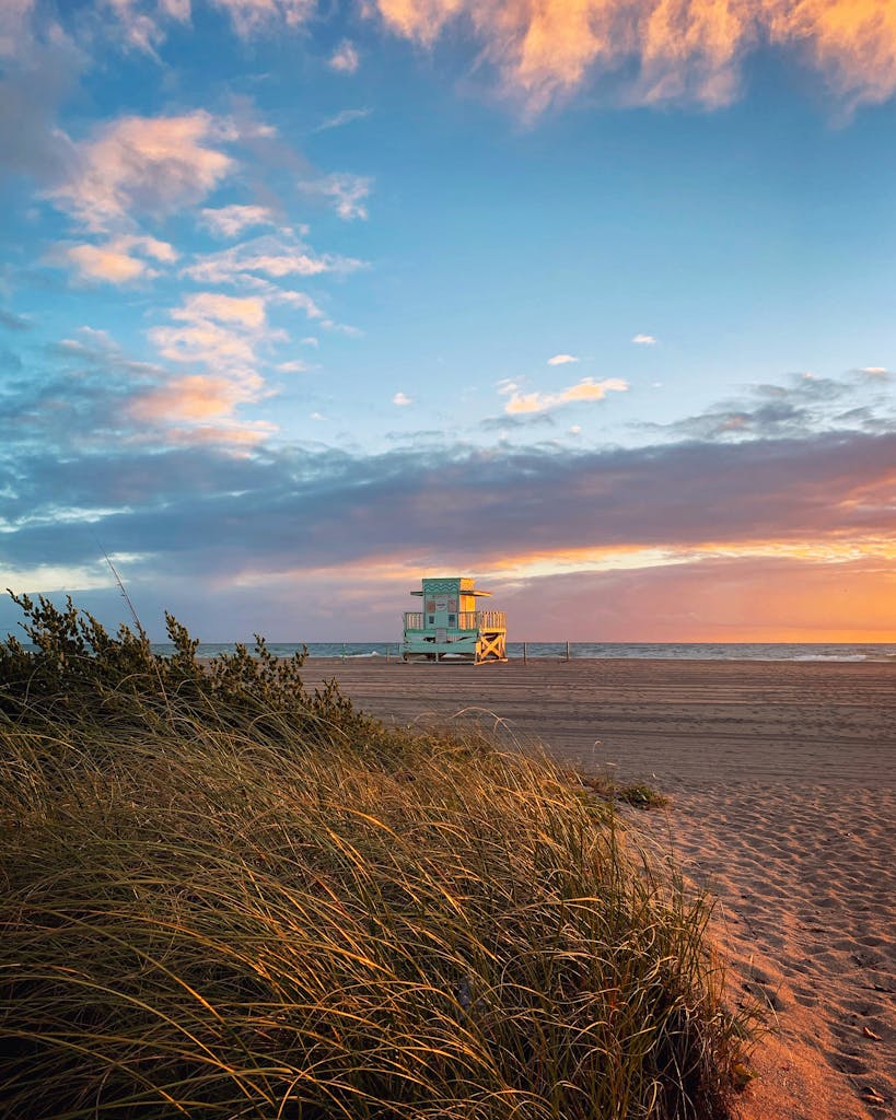 Stunning sunset over North Miami Beach with a lone lifeguard tower and serene coastline.